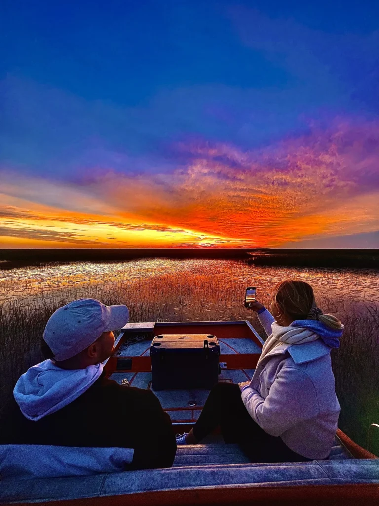 Guests watching a vivid Everglades sunset from the airboat