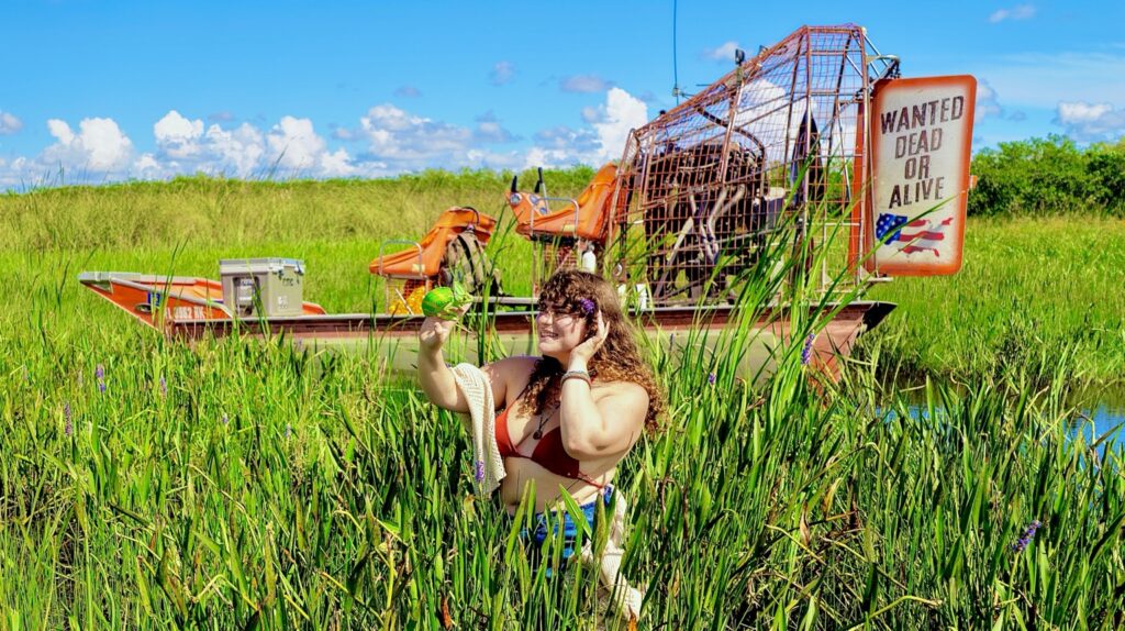 Guest with a green chameleon in front of an orange airboat