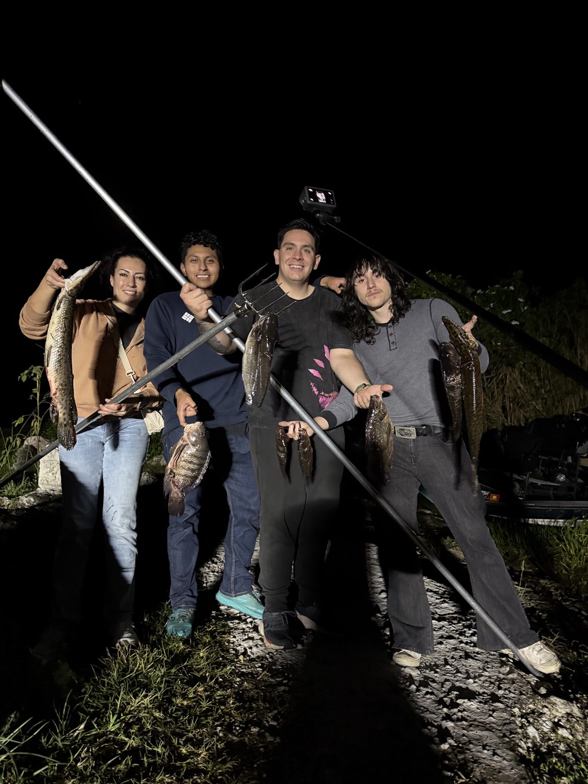 Guests with their catch and fish gigging equipment at night