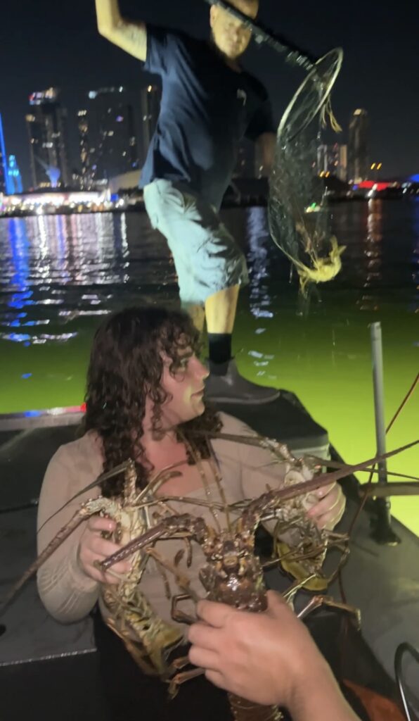 Guests with lobsters aboard a boat at night